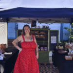 Arica Fernandez smiling at The Golden Grain farm stand, a St. Pete sourdough bakery